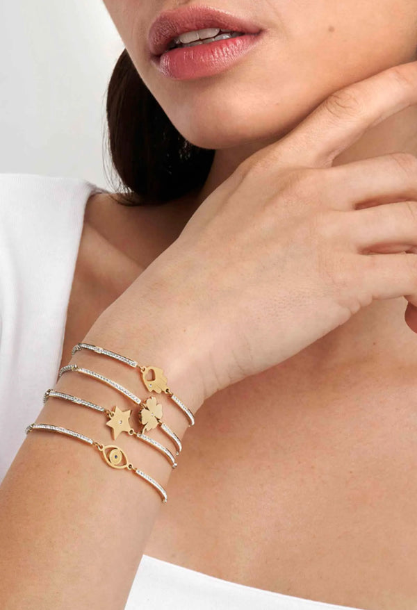 Woman wearing Nomination bracelet featuring hand of Fatima, clover, star, and evil eye charms on a delicate chain.