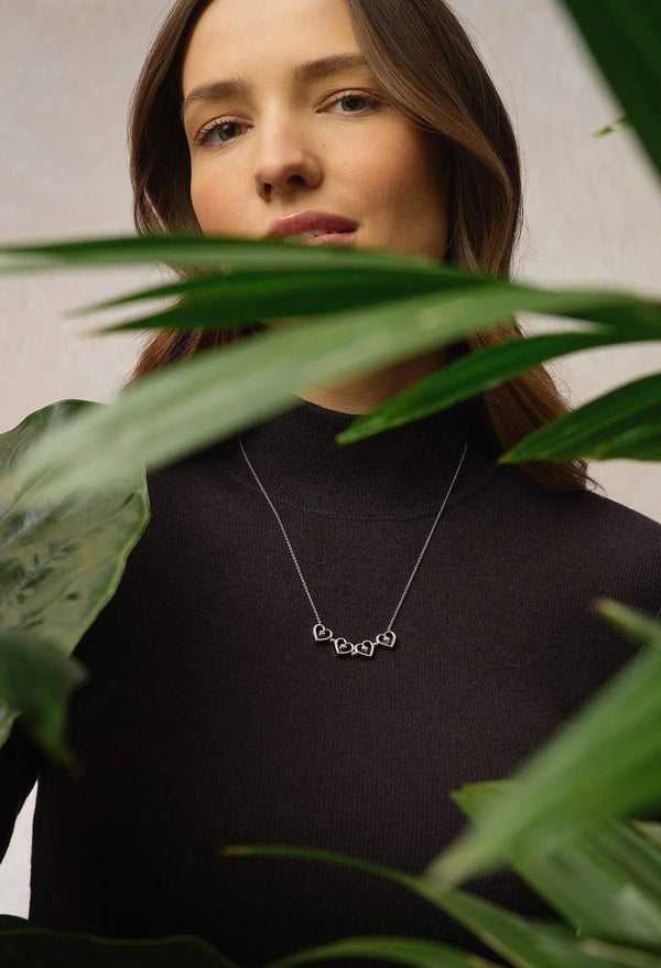 Woman wearing a Clogau Tree Of Life heart pendant necklace. Jewelry is focal point, displayed with style.