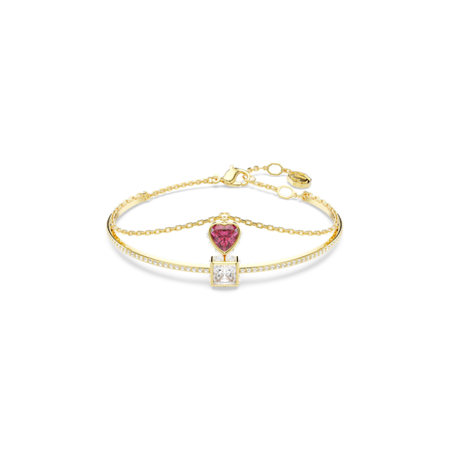 Gold plated Swarovski Stilla bangle featuring red heart and white square crystals, showcasing jewelry design and detail.