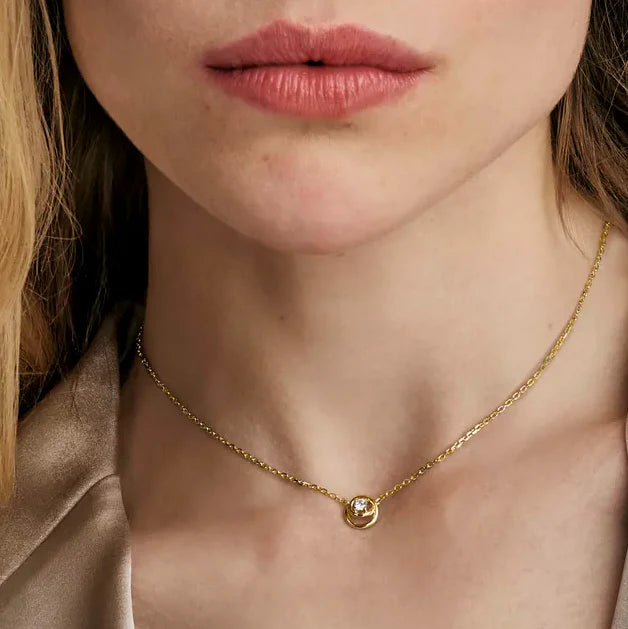 Nomination Cosmiclove necklace on model; gold chain with cubic zirconia circle pendant. Elegant jewelry.